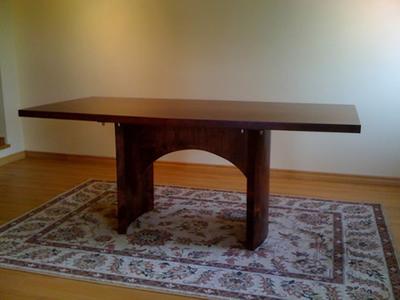 Dark wood conference table with arched end supports on a rug